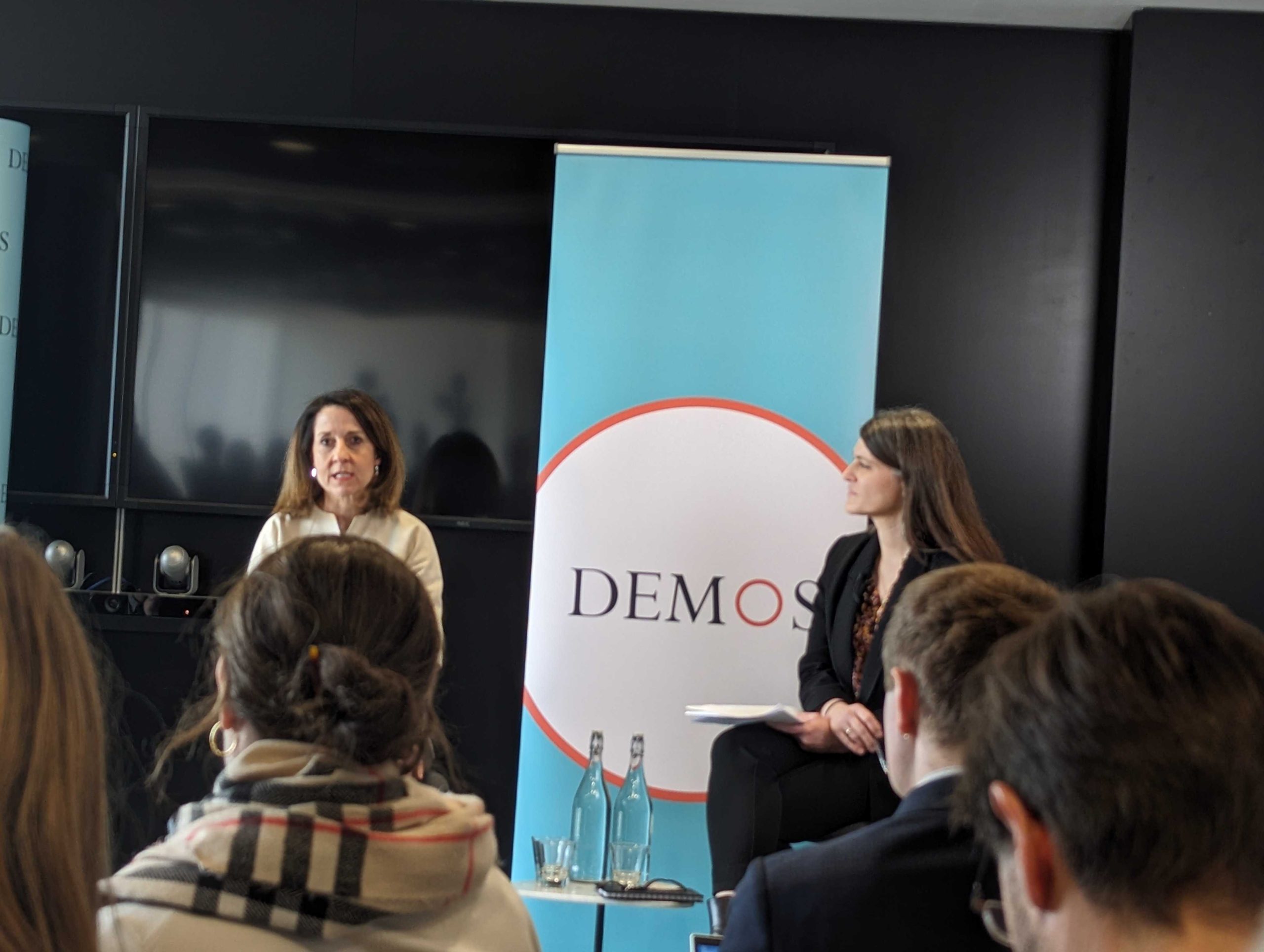 Women speaking infront of a demos banner