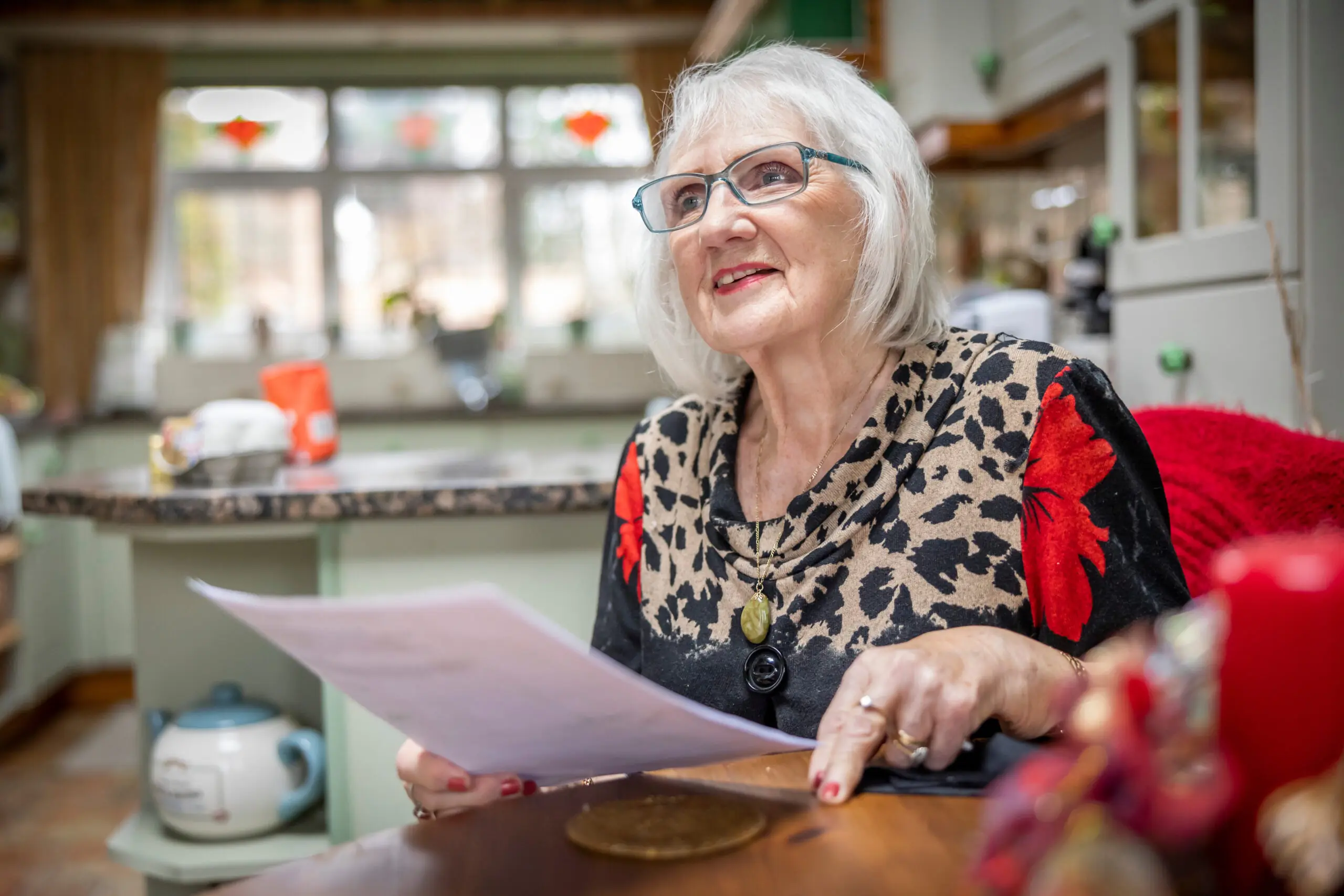Older lady looking at paperwork at her kitchen table